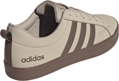 Ein beiger Adidas-Schuh mit braunen Streifen und Logo an der Seite. Ein beiger Adidas-Schuh mit braunen Streifen und Logo an der Seite.