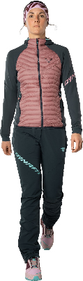 Eine Frau in einer rosafarbenen Daunenjacke und dunkelgrüner Hose mit Stirnband. Eine Frau in einer rosafarbenen Daunenjacke und dunkelgrüner Hose mit Stirnband.