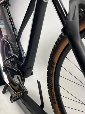 Detail eines modernen schwarzen E-Bikes mit braunen Rädern im Ständer. Detail eines modernen schwarzen E-Bikes mit braunen Rädern im Ständer.