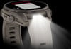 Eine Smartwatch mit weißem Armband und eingeschaltetem Licht oben.