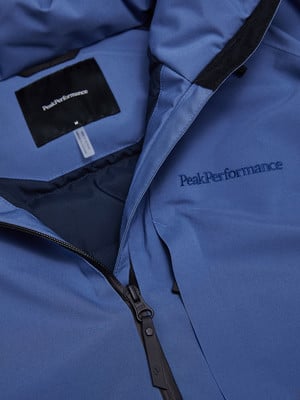 Blaue Jacke mit Peak Performance Logo und sichtbarem Reißverschluss. Blaue Jacke mit Peak Performance Logo und sichtbarem Reißverschluss.