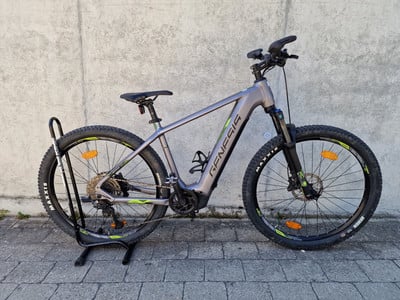 Graues E-Mountainbike mit Ständer und Reflektoren an den Rädern.