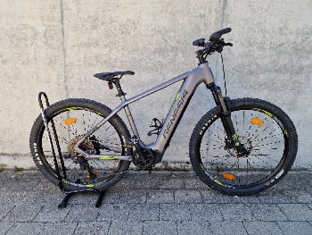 Graues E-Mountainbike mit Ständer und Reflektoren an den Rädern.