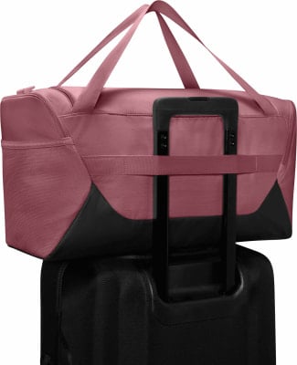 Eine rosafarbene Reisetasche mit schwarzen Details auf einem schwarzen Koffer. Eine rosafarbene Reisetasche mit schwarzen Details auf einem schwarzen Koffer.