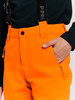 Detail einer orangefarbenen Hose mit Tasche und schwarzen Hosenträgern.