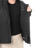 Ein Mann in einer schwarzen Jacke mit beiger Hose zeigt die Innentaschen.