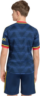 Junge in dunkelblauem Trikot mit rot-gelbem Saum und Shorts mit gelben Streifen. Junge in dunkelblauem Trikot mit rot-gelbem Saum und Shorts mit gelben Streifen.