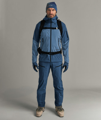 Ein Mann in einer blauen Skijacke, Hose, Mütze und Handschuhen mit Rucksack. Ein Mann in einer blauen Skijacke, Hose, Mütze und Handschuhen mit Rucksack.
