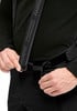 Ein Mann passt schwarze Hosenträger an schwarzer Hose an.