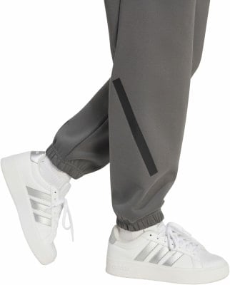 Graue Jogginghose mit schwarzem Streifen und weiße Sneaker mit Streifen. Graue Jogginghose mit schwarzem Streifen und weiße Sneaker mit Streifen.
