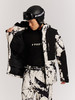 Mann in bedruckter Skijacke und Helm mit Brille.