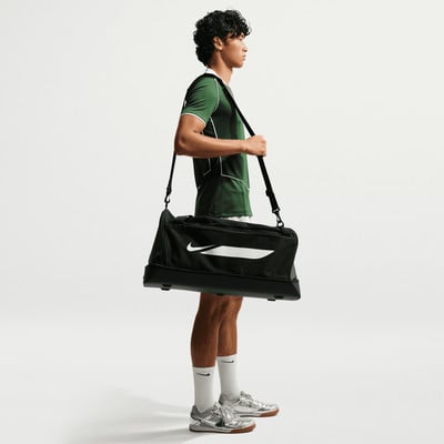 Ein Mann im grünen Hemd trägt eine schwarze Sporttasche über der Schulter. Ein Mann im grünen Hemd trägt eine schwarze Sporttasche über der Schulter.