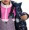 Das Mädchen trägt eine Winterjacke mit einem Baum- und Pinguinmotiv.