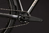 Detailaufnahme der Kurbel und Kette eines Mountainbikes vor dunklem Hintergrund.