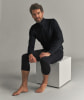 Ein Mann in einem schwarzen Langarmshirt und Dreiviertel-Leggings sitzt auf einem weißen Würfel.