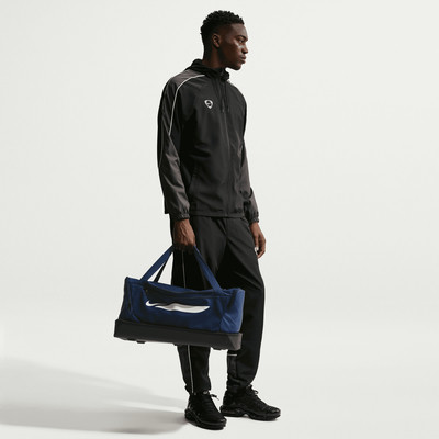 Ein Mann in schwarzer Sportkleidung hält eine dunkelblaue Tasche. Ein Mann in schwarzer Sportkleidung hält eine dunkelblaue Tasche.