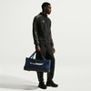 Ein Mann in schwarzer Sportkleidung hält eine dunkelblaue Tasche.