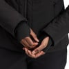 Detail der Hände in schwarzen Handschuhen mit Daumenlöchern und einer schwarzen Jacke.