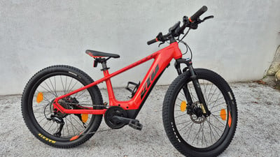 Ein rotes KTM E-Bike mit Federgabel und schwarzen Reifen.