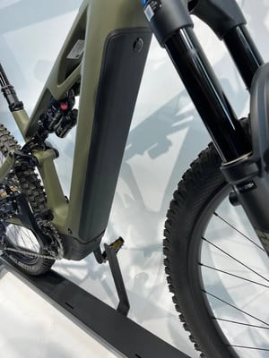 Grünes E-Bike mit schwarzem Akku und Federung auf einem Ständer. Grünes E-Bike mit schwarzem Akku und Federung auf einem Ständer.