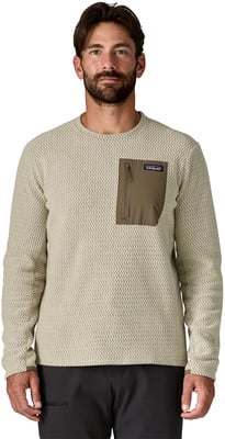 Ein Mann in einem beigen Pullover mit Reißverschlusstasche und Patagonia-Logo. Ein Mann in einem beigen Pullover mit Reißverschlusstasche und Patagonia-Logo.
