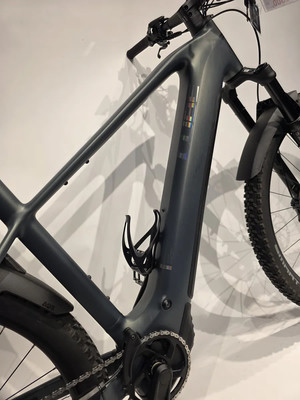 Rahmendetail eines dunkelgrauen E-Bikes mit buntem Logo und Flaschenhalter. Rahmendetail eines dunkelgrauen E-Bikes mit buntem Logo und Flaschenhalter.