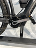 Detail eines Elektrofahrrads: Kette, Kurbeln und Rahmen mit Motor.