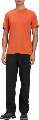 Ein Mann in einem orangefarbenen T-Shirt und schwarzer Hose mit Bergen auf der Brust. Ein Mann in einem orangefarbenen T-Shirt und schwarzer Hose mit Bergen auf der Brust.