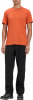 Ein Mann in einem orangefarbenen T-Shirt und schwarzer Hose mit Bergen auf der Brust.
