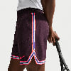 Mann in dunkelvioletten Shorts mit bunten Streifen hält einen Tennisschläger.