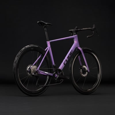 Lila Cube Rennrad mit schwarzen Rädern und Details auf dunklem Hintergrund. Lila Cube Rennrad mit schwarzen Rädern und Details auf dunklem Hintergrund.