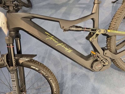 Schwarzes Mountain-E-Bike mit gelbem Schriftzug und Dämpfer. Schwarzes Mountain-E-Bike mit gelbem Schriftzug und Dämpfer.