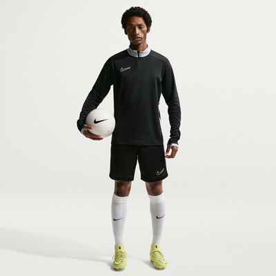 Ein Mann hält einen Fußball, gekleidet in einem schwarzen Trikot und Shorts. Ein Mann hält einen Fußball, gekleidet in einem schwarzen Trikot und Shorts.