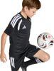 Ein Junge im schwarzen Fußballtrikot mit weißen Streifen spielt mit einem Ball.