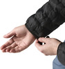 Eine Hand zieht den Ärmel einer schwarzen Daunenjacke zum Handgelenk.