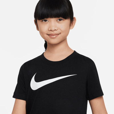 Ein Mädchen in einem schwarzen T-Shirt mit weißem Nike-Logo auf grauem Hintergrund. Ein Mädchen in einem schwarzen T-Shirt mit weißem Nike-Logo auf grauem Hintergrund.