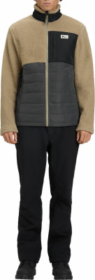 Ein Mann in einer beigefarbenen Fleecejacke mit schwarzer Steppung und schwarzer Hose. Ein Mann in einer beigefarbenen Fleecejacke mit schwarzer Steppung und schwarzer Hose.