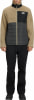 Ein Mann in einer beigefarbenen Fleecejacke mit schwarzer Steppung und schwarzer Hose.
