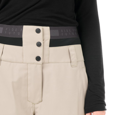 Detail einer Damen-Skihose in Beige mit schwarzem Bund und Knöpfen. Detail einer Damen-Skihose in Beige mit schwarzem Bund und Knöpfen.