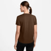 Eine Frau in einem braunen T-Shirt und schwarzer Leggings von hinten gesehen.