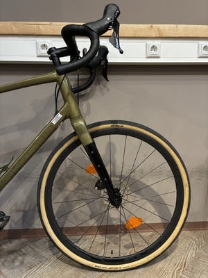 Ein grünes Gravelbike mit schwarzem Lenker und beigen Reifen. Ein grünes Gravelbike mit schwarzem Lenker und beigen Reifen.