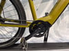 Detail eines gelben E-Bikes mit Kette und Kurbeln.
