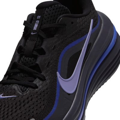 A Nike fekete futócipő részlete lila logóval és kék csíkokkal. A Nike fekete futócipő részlete lila logóval és kék csíkokkal.