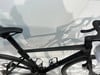 Ein schwarzes Rennrad mit schmalem Lenker und Schattenreflexion an der Wand.