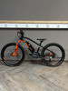 Schwarzes E-Bike mit orangefarbenen Details auf Holzboden.