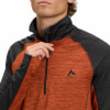 Ein Mann schließt einen orangefarbenen McKinley-Pullover mit grauen Ärmeln.