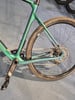 Grüner Fahrradrahmen mit Kette und Pedal auf blauem Hintergrund.