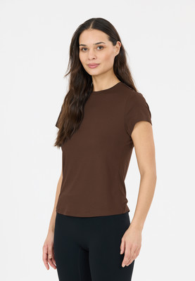 Eine Frau in einem braunen Oberteil und schwarzen Leggings steht in Pose. Eine Frau in einem braunen Oberteil und schwarzen Leggings steht in Pose.