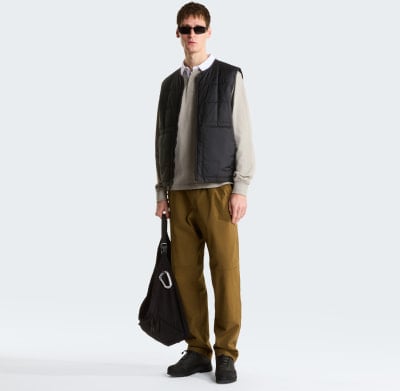 Mann in einem beigefarbenen Poloshirt, schwarzer Weste und brauner Hose. Mann in einem beigefarbenen Poloshirt, schwarzer Weste und brauner Hose.