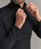 Ein Mann schließt einen schwarzen Pullover mit halbem Reißverschluss am Kragen.